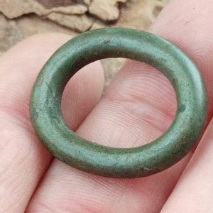 Op de afbeelding: Een groene metalen ring met een glad, afgerond oppervlak.