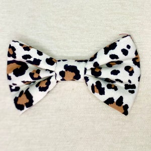 May include: A white bow tie with a brown and black leopard print pattern.