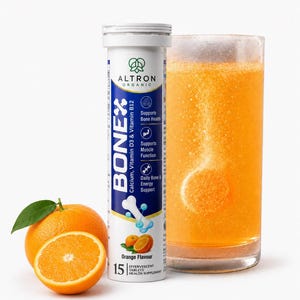 May include: A white cylindrical tube of Altron Organic Bonex effervescent tablets with blue and orange branding, next to a glass of orange liquid with a dissolving tablet and two fresh oranges, one whole and one sliced in half with a green leaf.