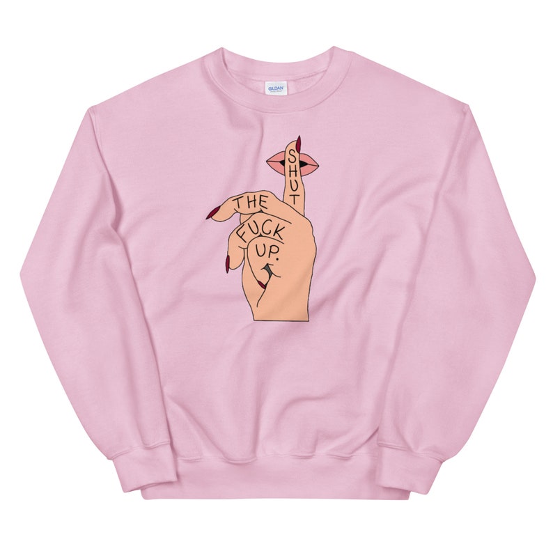 May include: Pink sweatshirt with a graphic of a hand with a finger over its mouth, with the text "SHUT THE FUCK UP."