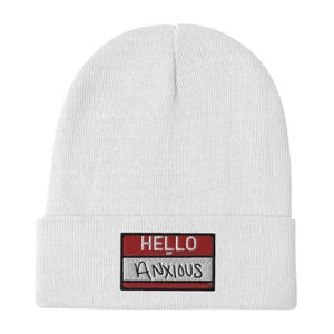 May include: White knit beanie with a red and gray name tag that says "HELLO ANXIOUS" in black embroidery.