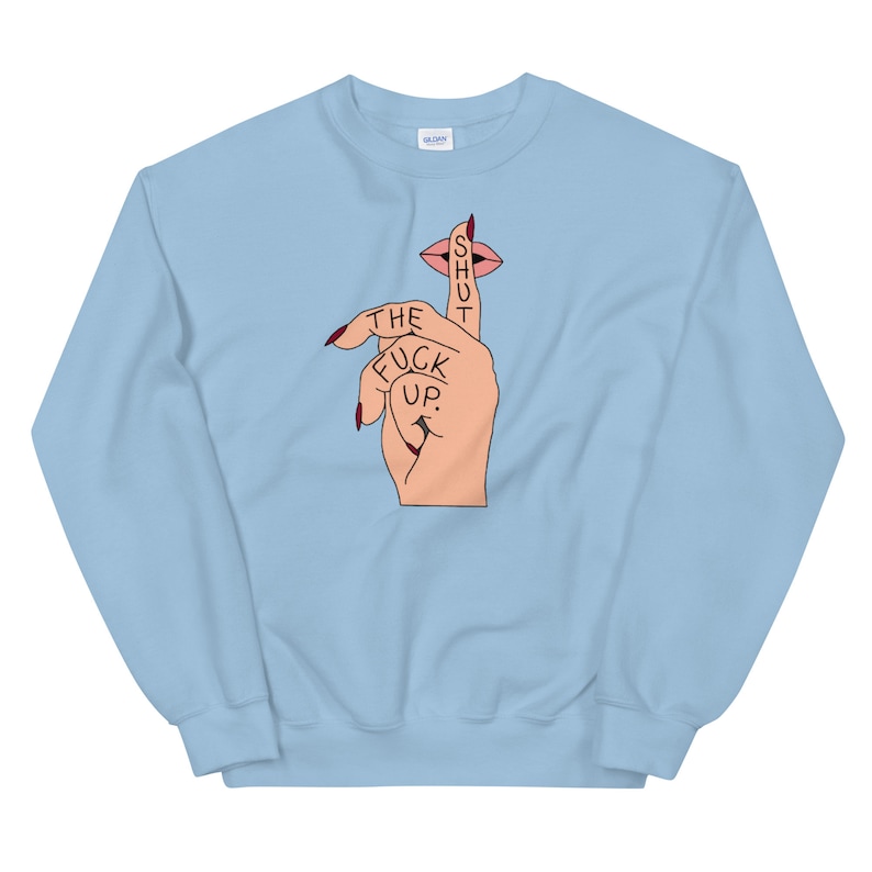 May include: Light blue sweatshirt with a graphic of a hand with a finger over its mouth, with the text "SHUT THE FUCK UP." printed on the finger.