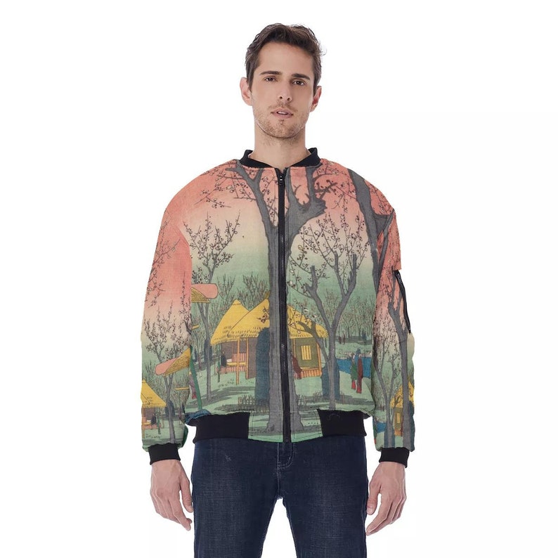 May include: A bomber jacket featuring a Japanese landscape design with a village scene, trees, and a sunset. The jacket has a black zipper, cuffs, and hem. The design is printed on a light-colored fabric.