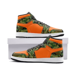 May include: High-top sneakers with a vibrant orange and camouflage pattern. The shoes feature a white sole, black accents, and gray laces. The design incorporates a mix of orange and green camouflage panels.
