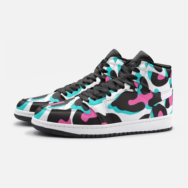 May include: High-top sneakers with a white sole and black laces. The shoes feature a pattern of black, pink, and teal shapes on a white background. The collar and tongue are black.