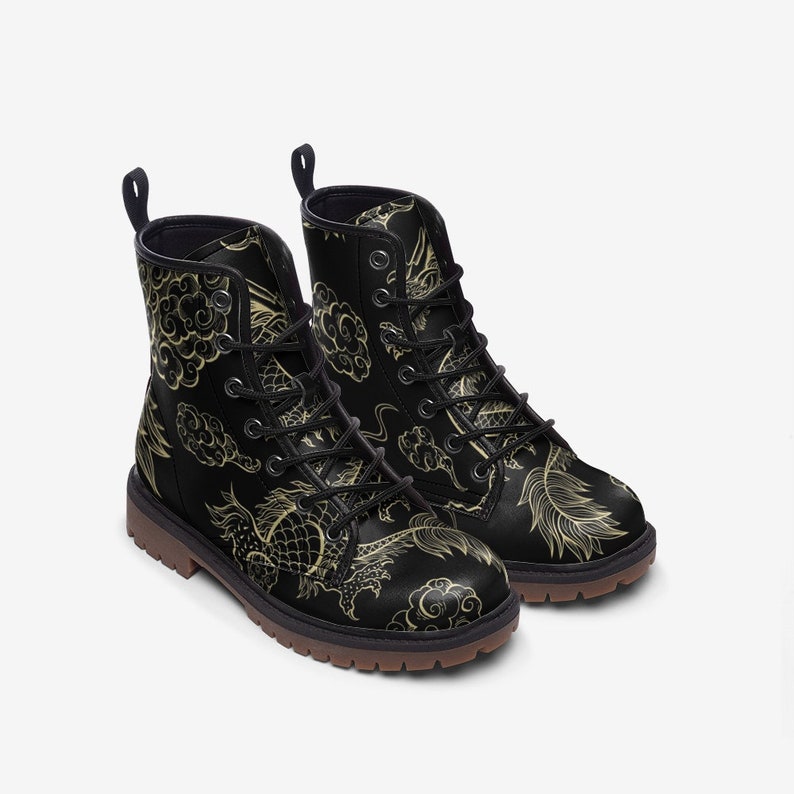 Puede incluir: Botas de combate negras con un dise&ntilde;o de drag&oacute;n y nubes doradas. Las botas tienen cordones negros, una leng&uuml;eta y una suela marr&oacute;n. El dise&ntilde;o est&aacute; inspirado en el arte asi&aacute;tico.