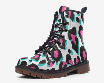 May include: A pair of lace-up combat boots with a white background and a colorful leopard print pattern. The pattern features black, pink, and teal spots. The boots have a brown sole and black laces.