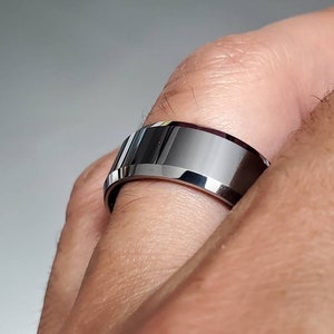 以下が含まれることがあります： 銀色のタングステンカーバイド製のリングで、斜めになったエッジとブラッシュ仕上げが施されています。