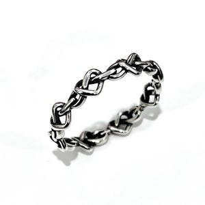 May include: A silver ring with a delicate, intertwined heart design. The ring is made of a smooth, polished metal and has a simple, elegant style.