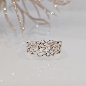 May include: A silver filigree ring with a delicate floral design.