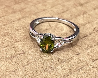 May include: A silver ring with a green oval gemstone set in a Celtic knot design.
