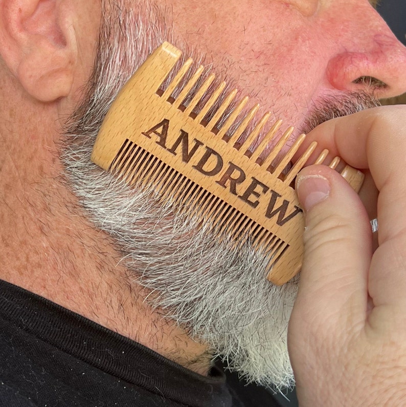 K&ouml;nnte beinhalten: Ein Holzkamm mit dem eingravierten Namen "ANDREW". Der Kamm wird verwendet, um den Bart eines Mannes zu stylen.