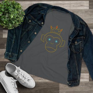 May include: A gray raglan shirt featuring a yellow outline of a monkey wearing a crown with the text "Bad Sensei". The shirt is paired with a denim jacket and white sneakers, creating a casual, streetwear aesthetic.