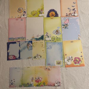 Op de afbeelding: Een verzameling rechthoekige briefpapierbladen met diverse kleurrijke illustraties van tekenfilmmuizen, bloemmotieven en geruite of lege schrijfgebieden. Elk vel toont unieke ontwerpen met zachte pastelkleurige achtergronden en kleine motieven.