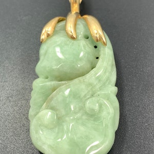 May include: A green jade pendant carved with a floral design, set in a gold pendant bail.
