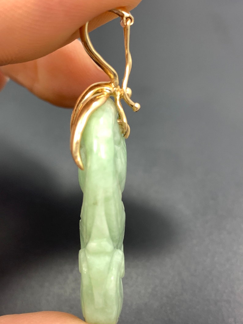 May include: A pair of green jade earrings with gold leaf accents and a gold hook closure.