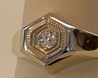 May include: A gold ring with a hexagonal setting featuring a single, clear diamond.