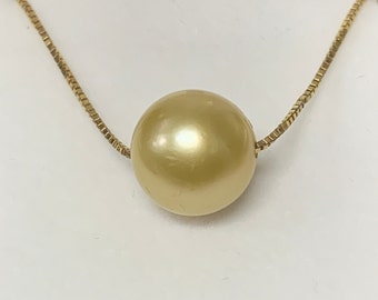 May include: A gold chain necklace with a single large golden pearl pendant.