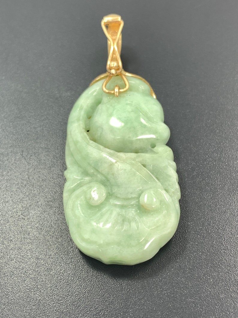 May include: A green jade pendant carved with a floral design, suspended from a gold chain.