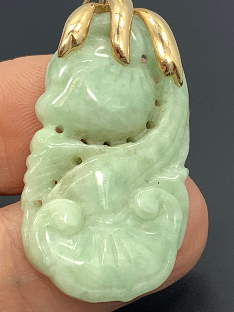May include: A green jade pendant carved with a floral design, set in a gold bail.