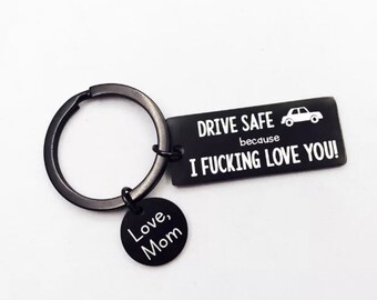 May include: Black keychain with a round ring and two charms. One charm is rectangular with the text "DRIVE SAFE because I FUCKING LOVE YOU!" and a car graphic. The other charm is round and says "Love, Mom."