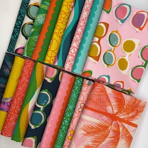 May include: A collection of folded fabric bundles featuring various colorful patterns. Designs include sunglasses, tropical leaves, and geometric shapes in shades of pink, green, yellow, and blue. The fabrics are arranged on a white surface.