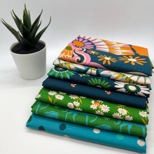 May include: A stack of eight fabric squares with different colorful patterns. The patterns include a teal background with orange and white flowers, a green background with white flowers, and a teal background with white polka dots.