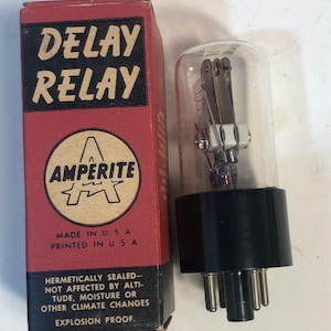 May include: A vintage electronic delay relay with a clear glass enclosure and black base, next to its original red box. The box features the text "DELAY RELAY" and "AMPERITE" branding, with additional text indicating it's made in the USA.