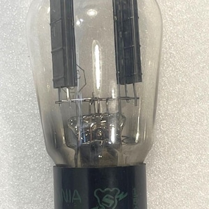 May include: A vintage vacuum tube with a clear glass bulb and black internal components. The base is black with the text "Sylvania USA" and a logo. The tube has multiple pins for connection.