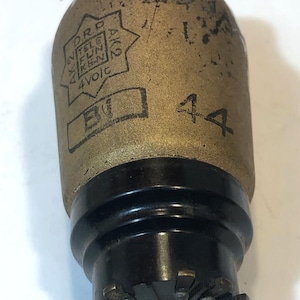 May include: Vintage vacuum tube with a brass-colored body and black base. The tube has the text "D.R.P. TELE FUN KEN AK2" and "4 Volts" printed on it. The number "44" is also visible on the side.