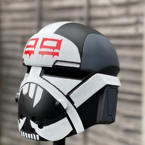 May include: A black, white, and gray helmet with red accents. The helmet features a skull-like design on the front and the number "29" in red on the top. The helmet is painted with a distressed, worn look.
