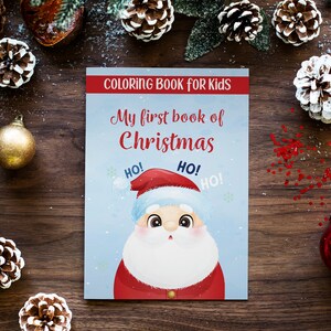 Peut inclure: Un livre de coloriage bleu avec un P&egrave;re No&euml;l en dessin anim&eacute; sur la couverture. Le livre est intitul&eacute; "Mon premier livre de No&euml;l" et contient les mots "HO!" r&eacute;p&eacute;t&eacute;s trois fois.