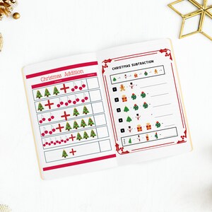 Peut inclure: Un cahier d'exercices d'addition et de soustraction sur le th&egrave;me de No&euml;l avec des illustrations rouges et vertes de sapins de No&euml;l, de boules, de cadeaux et d'un bonhomme de neige. Le cahier a une bordure rouge et les mots "Christmas Addition" et "Christmas Subtraction" sont imprim&eacute;s sur la couverture.
