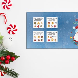 Peut inclure: Un livre bleu et blanc intitul&eacute; "I Spy Christmas Book for Kids". La couverture pr&eacute;sente un P&egrave;re No&euml;l de dessin anim&eacute; avec une couronne de houx et des cloches.