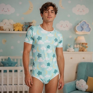 May include: A light blue short-sleeve bodysuit featuring a repeating pattern of smiling white clouds, yellow crescent moons, and teal stars. The garment has a white crew neckline and white trim along the leg openings, providing a fitted silhouette.