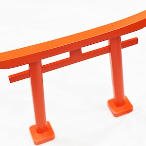 Könnte beinhalten: Ein traditionelles japanisches Torii-Tor aus Holz, in leuchtendem Orange lackiert. Das Tor ist ein häufiger Anblick an Shinto-Schreinen und wird oft als Symbol für den Übergang verwendet.