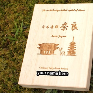 Op de afbeelding: Een houten doos met een lasergegraveerd ontwerp met een pagode, een hert en een poort. De doos is beschreven met de tekst "The world heritage/oldest capital of Japan", "日本古都奈良", "Nara Japan", "Omamori lucky charm for you" en "your name here".
