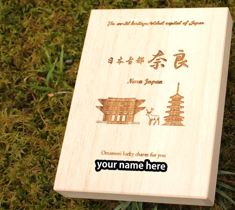 Op de afbeelding: Een houten doos met een lasergegraveerd ontwerp met een pagode, een hert en een poort. De doos is beschreven met de tekst "The world heritage/oldest capital of Japan", "日本古都奈良", "Nara Japan", "Omamori lucky charm for you" en "your name here".