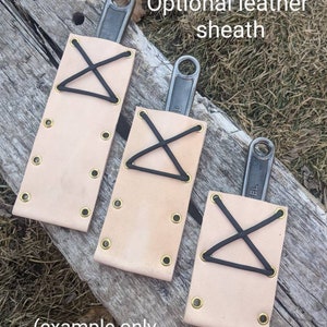 K&ouml;nnte beinhalten: Drei Ledertaschen mit schwarzen Gummib&auml;ndern und Messingnieten. Die Taschen sind f&uuml;r Schraubenschl&uuml;ssel konzipiert. Der Text "Optional leather sheath" ist &uuml;ber den Taschen sichtbar. Der Text "(example only, individual units vary)" ist unter den Taschen sichtbar.