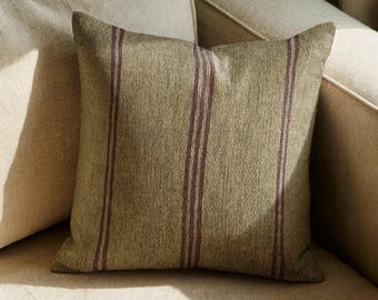 Può includere: Un cuscino quadrato in tessuto testurizzato verde oliva con strisce verticali di un colore bordeaux intenso. Il cuscino presenta un aspetto intrecciato uniforme sulla superficie anteriore, mostrando un design semplice con linee dritte e pulite.