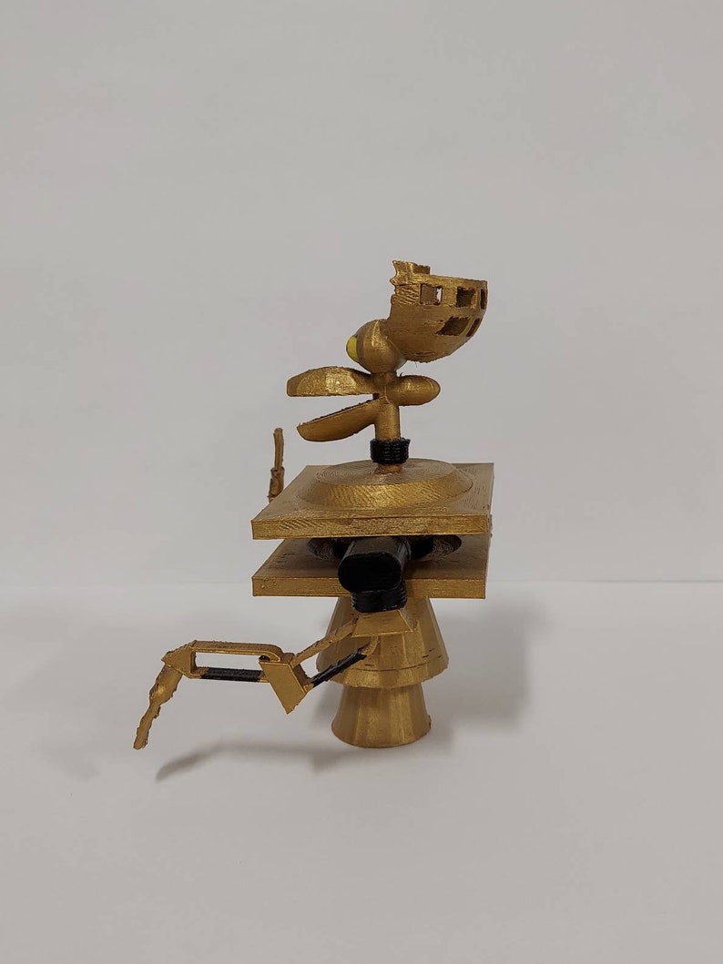 May include: A gold-colored 3D printed robot with a square base, a round base, and a head with a propeller. The robot has a single arm with a claw.