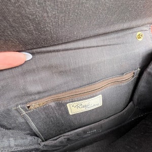 May include: The inside of a black handbag with a zipped pocket and a label that reads "a Risque handbag".