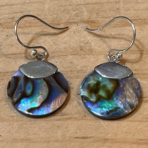 May include: A pair of silver dangle earrings with iridescent abalone shell round pendants.