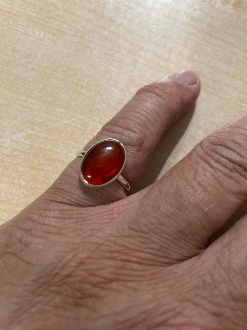 May include: A silver ring with a red oval gemstone.