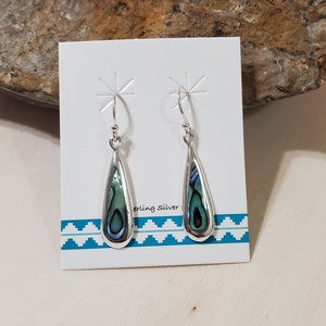 May include: A pair of sterling silver earrings with teardrop-shaped abalone shell inlays. The earrings are displayed on a white card with the text "Sterling Silver".