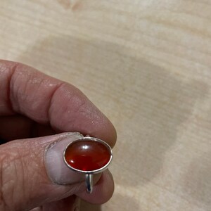 May include: A silver ring with a red oval gemstone.