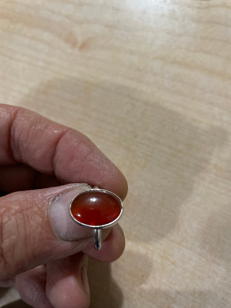 May include: A silver ring with a red oval gemstone.