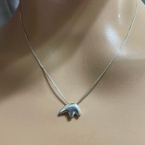 May include: A silver chain necklace with a small, silver bear pendant.