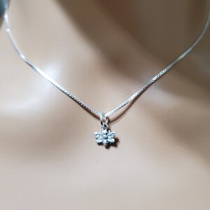 May include: A silver chain necklace with a small silver bee pendant.