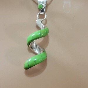 May include: A silver necklace with a green turquoise pendant in the shape of a spiral.